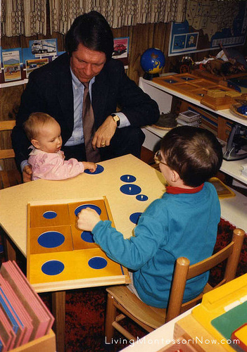 Christina (9 months), Terry, and Will (5). Montessori education encourages kindness and older children helping younger children. Here Will decided to introduce his baby sister to one of the Montessori geometric trays.